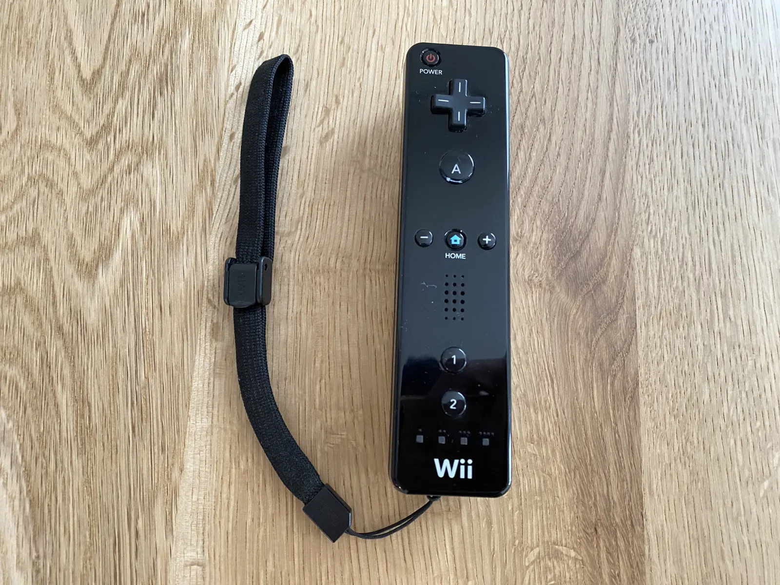 ストラップを取り付けた黒いWiiリモコン